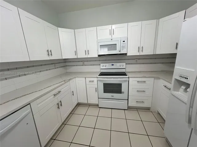a kitchen with white cabinets and appliances