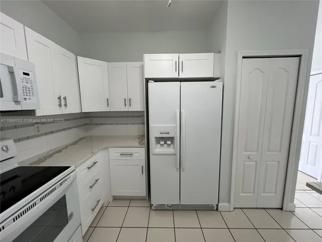 a kitchen with white cabinets and white appliances