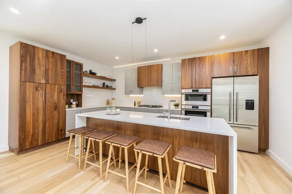 a kitchen with stainless steel appliances granite countertop a refrigerator a stove a sink dishwasher and white cabinets with wooden floor