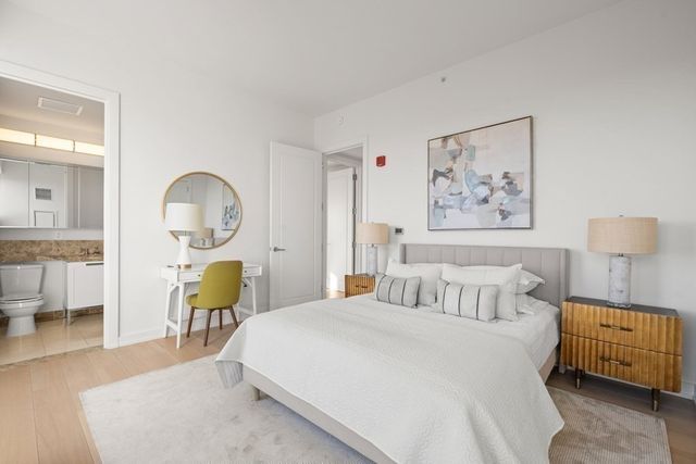 a bedroom with a bed chair table and painting on the wall