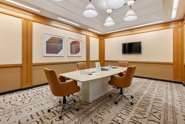 a view of a dining table and chairs in a hall with a large window