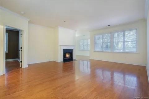 5601 Fairview Road, Unit 26 Charlotte, NC 28209 - Photo 19 of 22 an empty room with wooden floor fireplace and windows