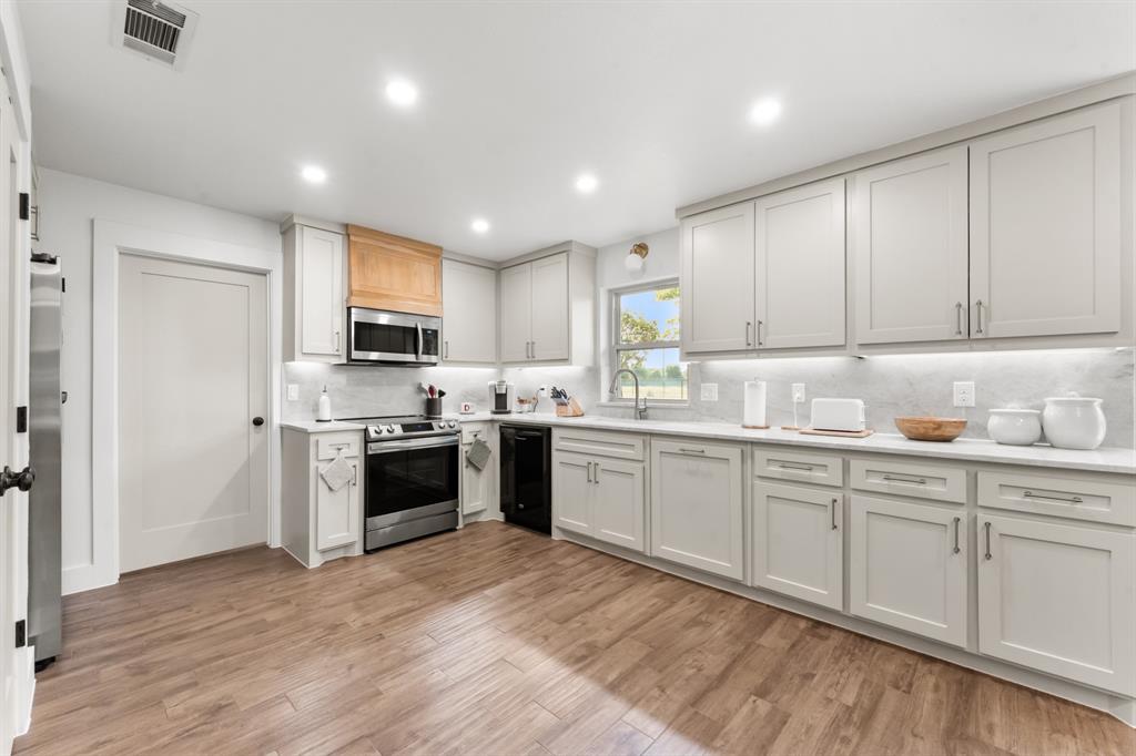380 Farr Altom Road Seagoville, TX 75159 - Photo 5 of 30 Kitchen featuring recessed lighting, light-toned cabinetry, stainless steel appliances, wood-finish flooring, and white countertops with a matching backsplash