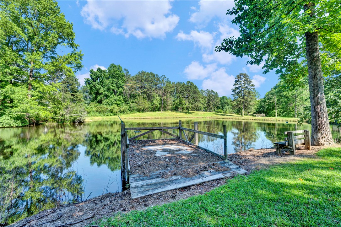 7876 Highway 11 Walhalla, SC 29691 - Photo 6 of 35 A tranquil pond reflecting vibrant greenery and blue skies offers a serene escape, complete with a small private dock.
