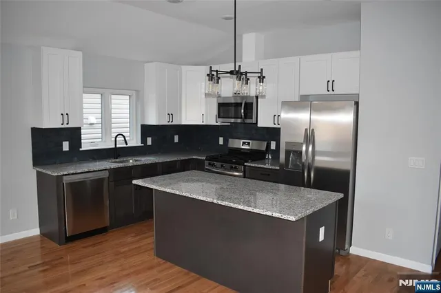 a kitchen with stainless steel appliances granite countertop a sink a stove and refrigerator