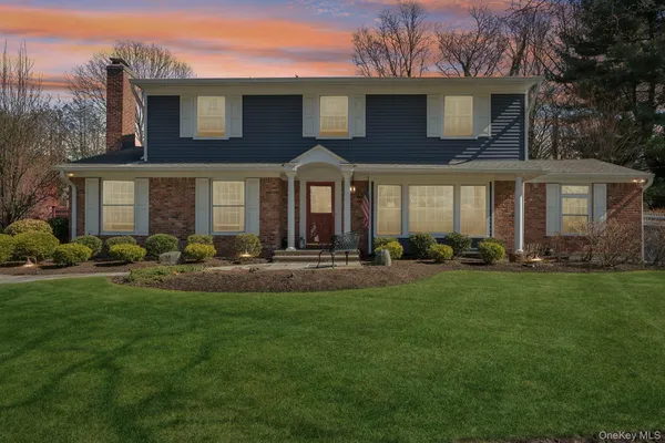 a front view of a house with a yard and trees
