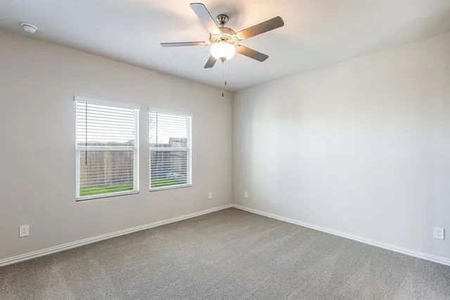 an empty room with chandelier fan and windows
