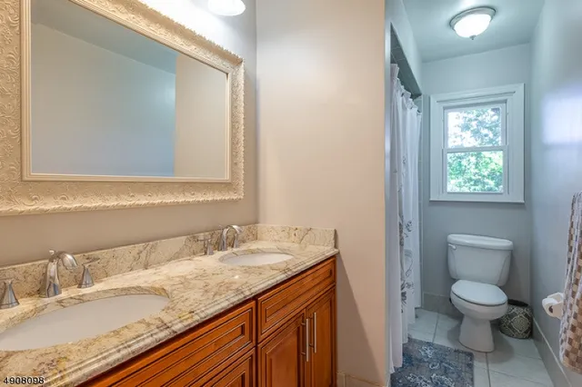 a bathroom with a granite countertop sink toilet and mirror