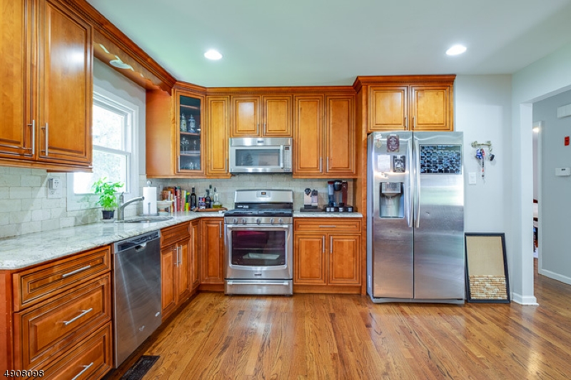 14 Ash Lane Randolph, NJ 07869 - Photo 4 of 22 a kitchen with stainless steel appliances granite countertop a refrigerator a sink dishwasher and wooden cabinets with wooden floor