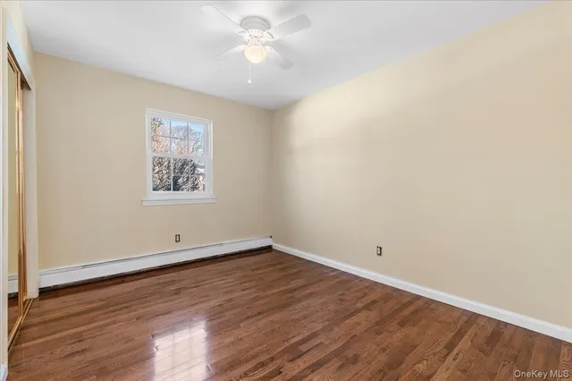an empty room with wooden floor and ceiling fan