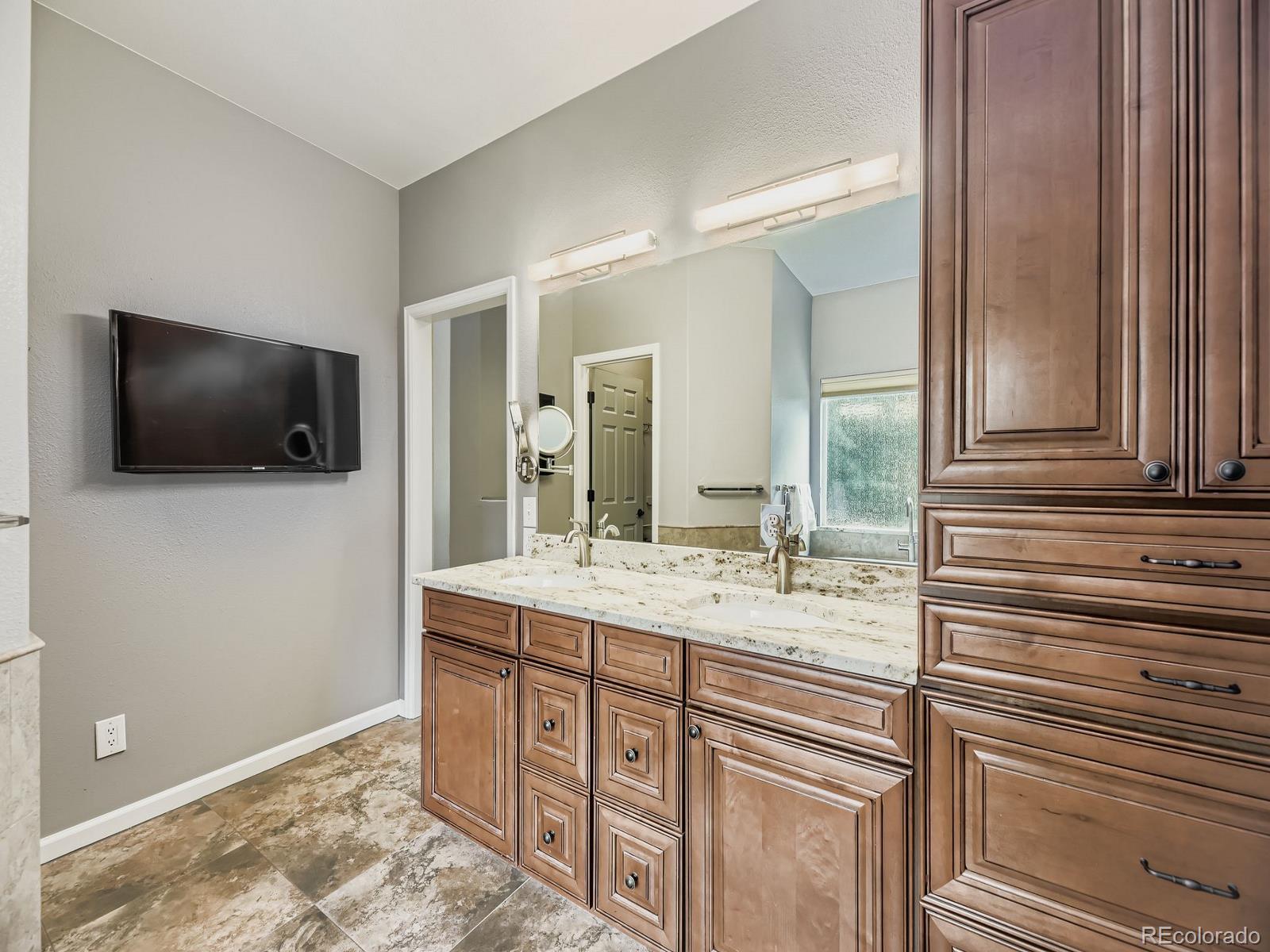 15906 Double Eagle Drive Morrison, CO 80465 - Photo 15 of 34 a bathroom with a sink a large mirror and a wooden cabinet