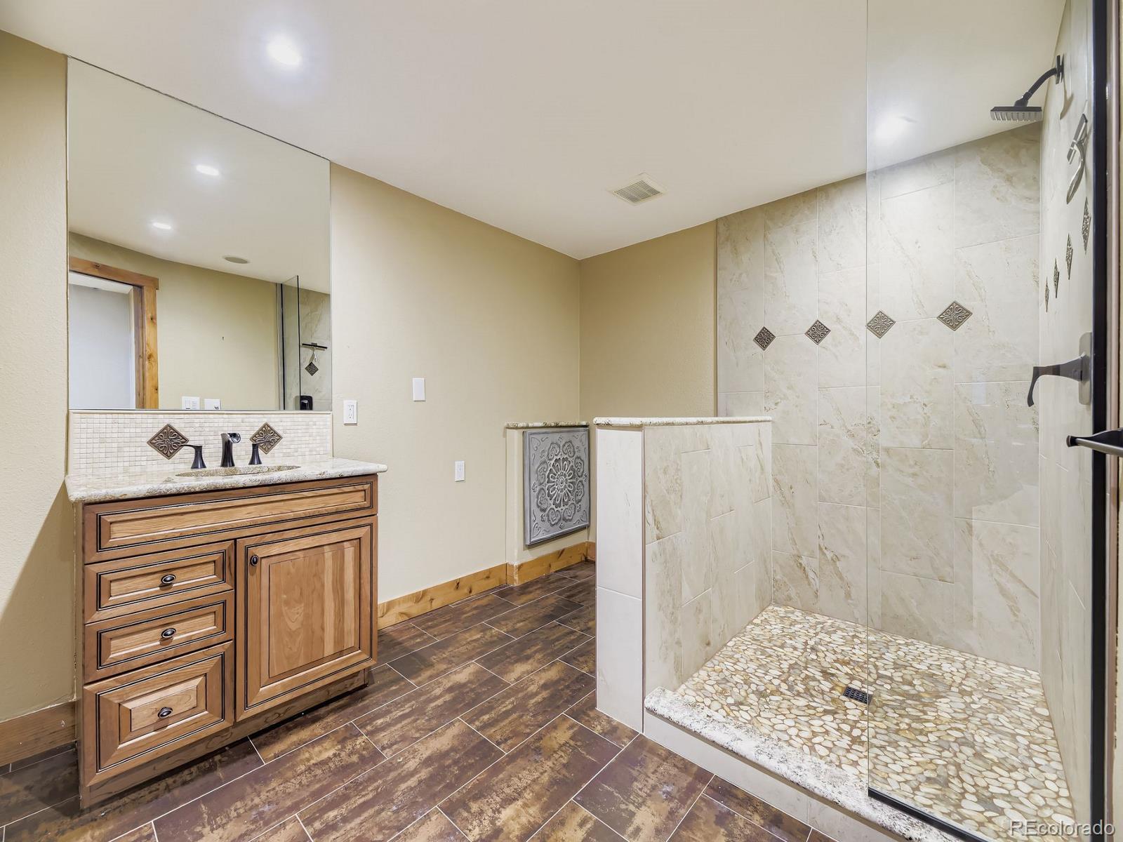 15906 Double Eagle Drive Morrison, CO 80465 - Photo 28 of 34 a bathroom with a granite countertop sink a mirror and shower