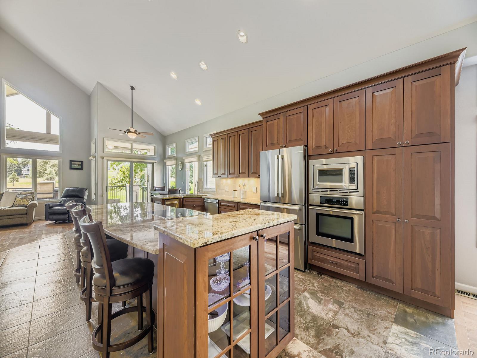 15906 Double Eagle Drive Morrison, CO 80465 - Photo 3 of 34 a kitchen with stainless steel appliances granite countertop a stove a refrigerator a sink a dining table and chairs with wooden floor