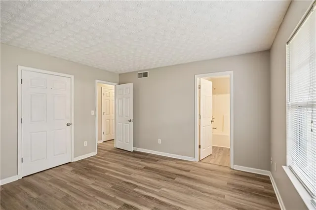 a view of an empty room with wooden floor and window
