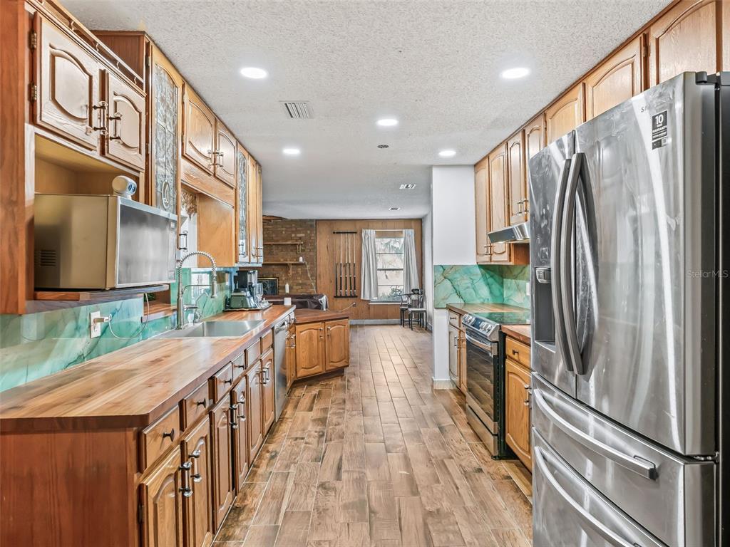 6350 Northeast 86th Avenue Bronson, FL 32621 - Photo 20 of 92 a kitchen with stainless steel appliances granite countertop a refrigerator a sink dishwasher a stove and a dining table with wooden floor