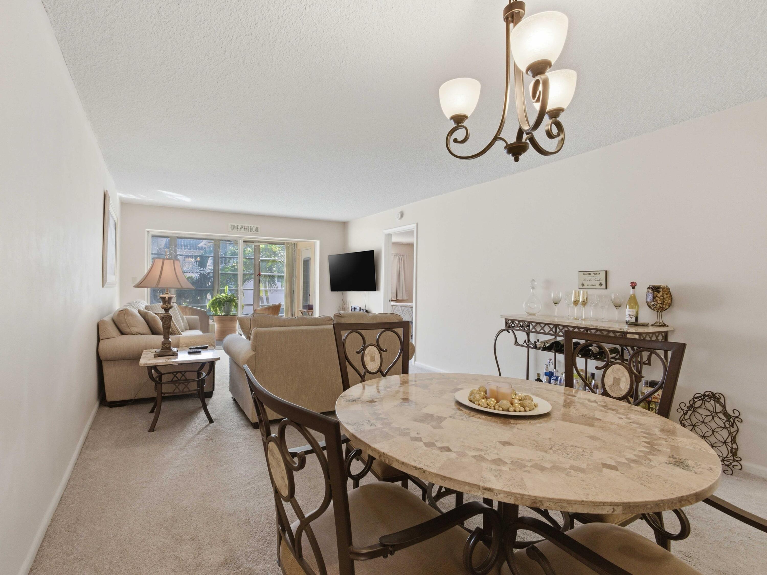 400 Northeast 20th Street, Unit A216 Boca Raton, FL 33431 - Photo 18 of 33 a view of a dining room with furniture a chandelier and wooden floor