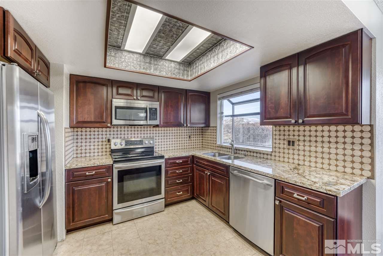 2741 Pajaro Place Reno, NV 89502 - Photo 14 of 36 a kitchen with stainless steel appliances granite countertop a stove sink and cabinets