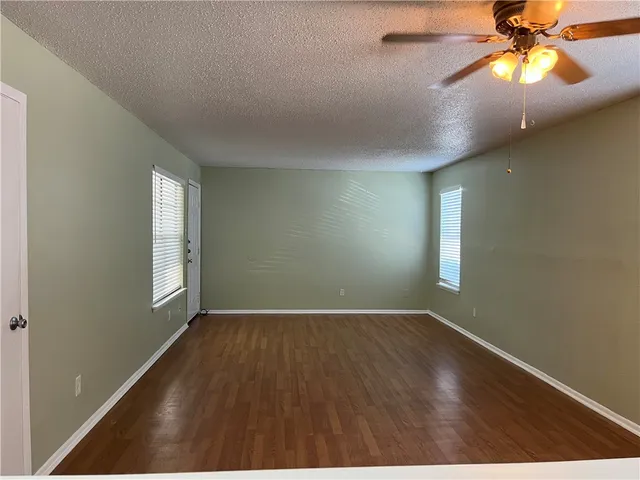 an empty room with windows and fan