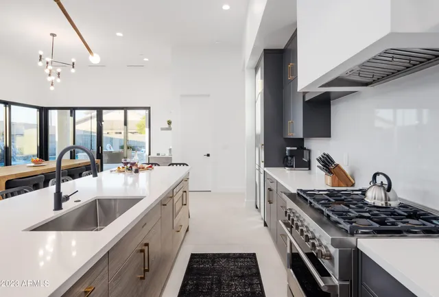 a kitchen with stainless steel appliances kitchen island granite countertop a table chairs sink and cabinets