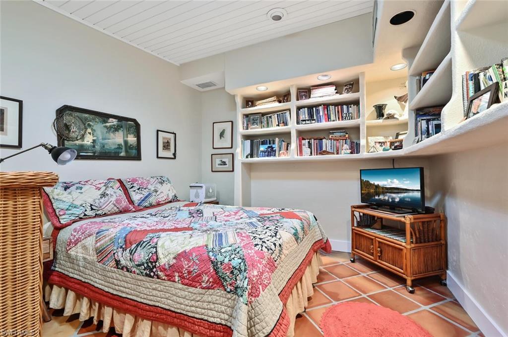 3113 Basin Street Naples, FL 34112 - Photo 28 of 49 a bedroom with a bed a bookshelf and painting on the wall