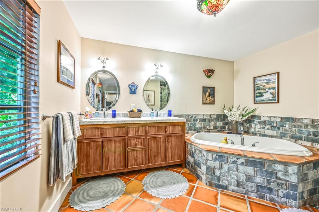 3113 Basin Street Naples, FL 34112 - Photo 32 of 49 a spacious bathroom with a tub a double vanity sink and a mirror