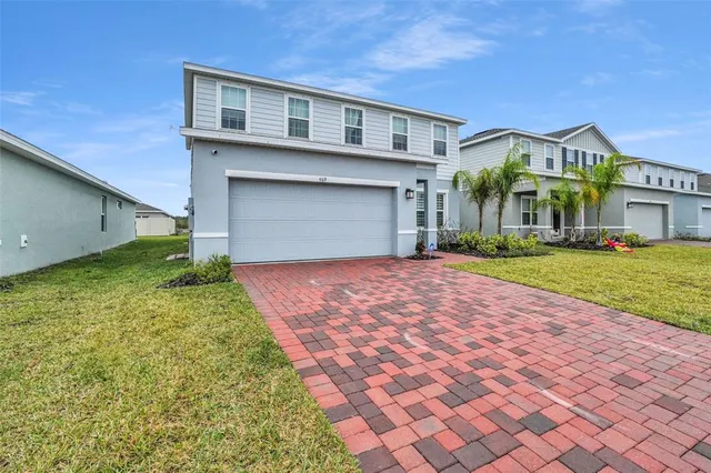 a front view of a house with a yard and potted plants