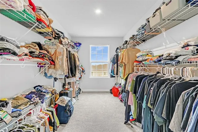 a view of walk in closet with clothes and shoes