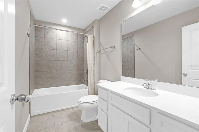 a bathroom with a bathtub shower sink vanity mirror and toilet