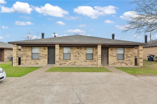 a front view of a brick building with a yard