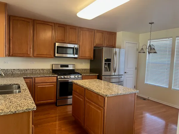 a kitchen with kitchen island wooden cabinets a refrigerator stove and microwave