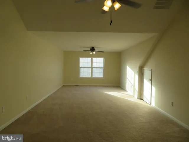 an empty room with windows and chandelier fan