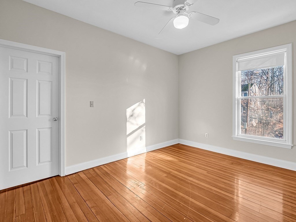 775 Bridge Street Lowell, MA 01850 - Photo 17 of 42 an empty room with wooden floor chandelier fan and windows