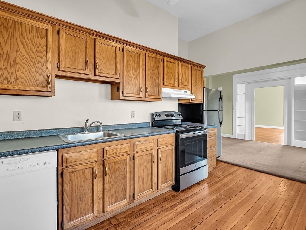 775 Bridge Street Lowell, MA 01850 - Photo 19 of 42 a kitchen with granite countertop wooden cabinets stainless steel appliances and a sink