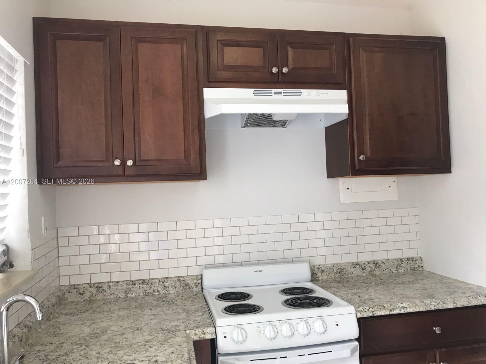 2483 Southwest 11th Street, Unit 2483 Miami, FL 33135 - Photo 7 of 12 a kitchen with granite countertop cabinets and white stove