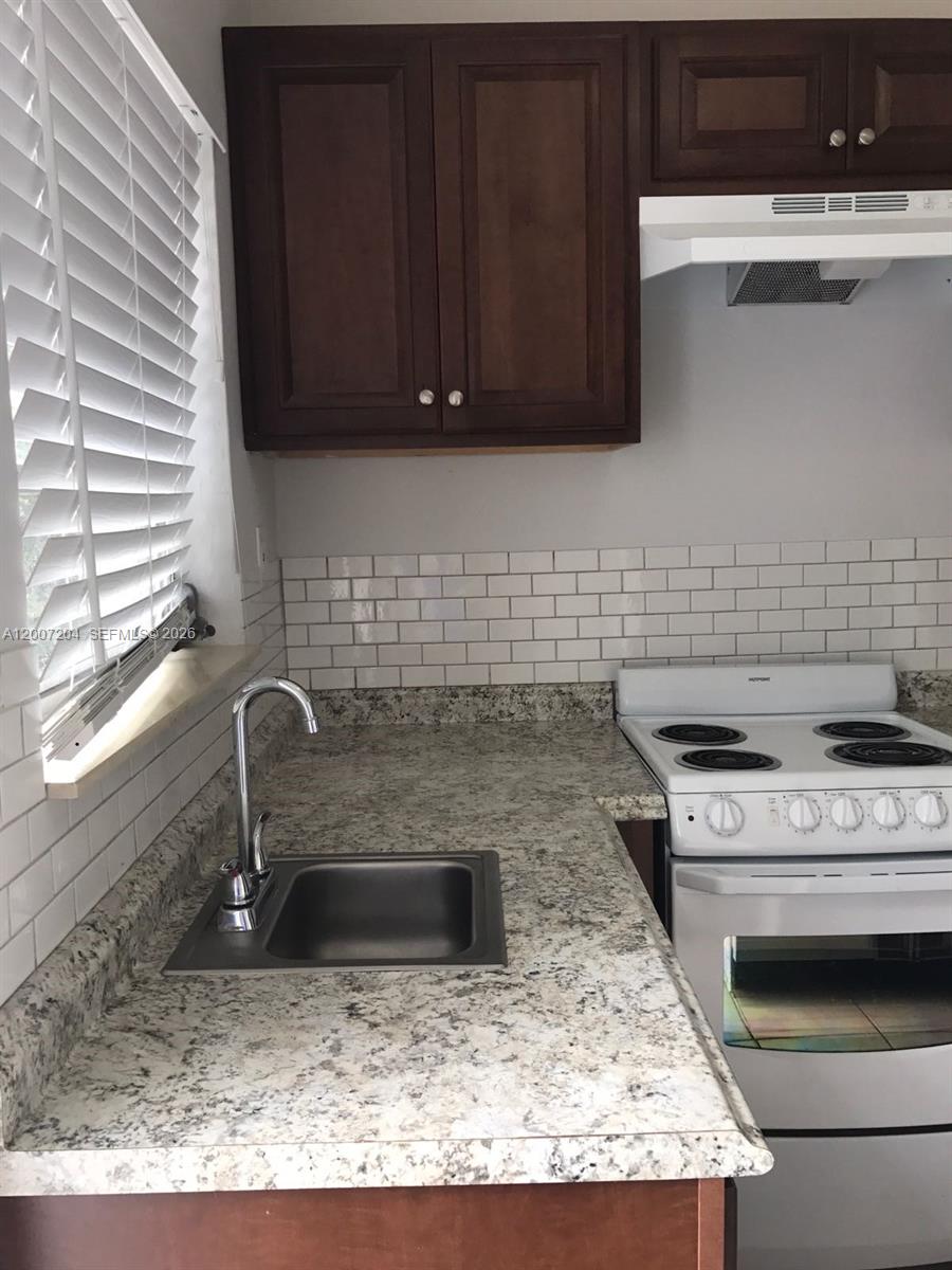 2483 Southwest 11th Street, Unit 2483 Miami, FL 33135 - Photo 8 of 12 a kitchen with granite countertop a sink a stove and cabinets