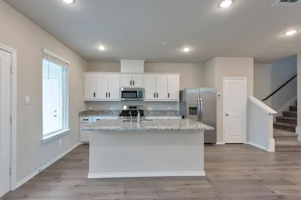 a large kitchen with stainless steel appliances lots of counter space and wooden floor