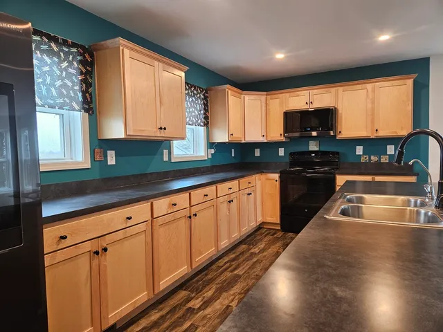 a kitchen with stainless steel appliances granite countertop a sink a stove cabinets counter space and a window