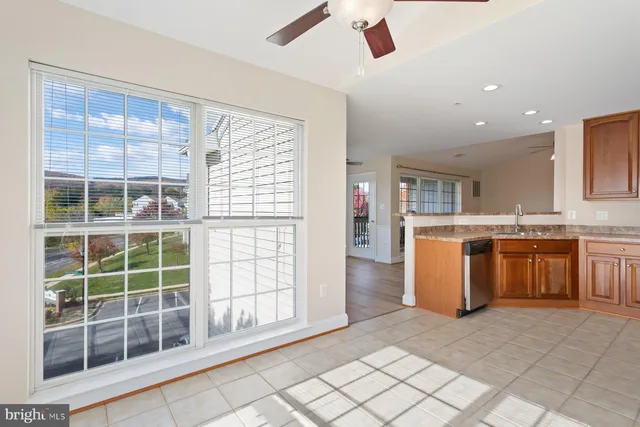 an empty room with chandelier fan and windows