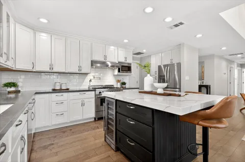 a kitchen with a sink white cabinets and stainless steel appliances