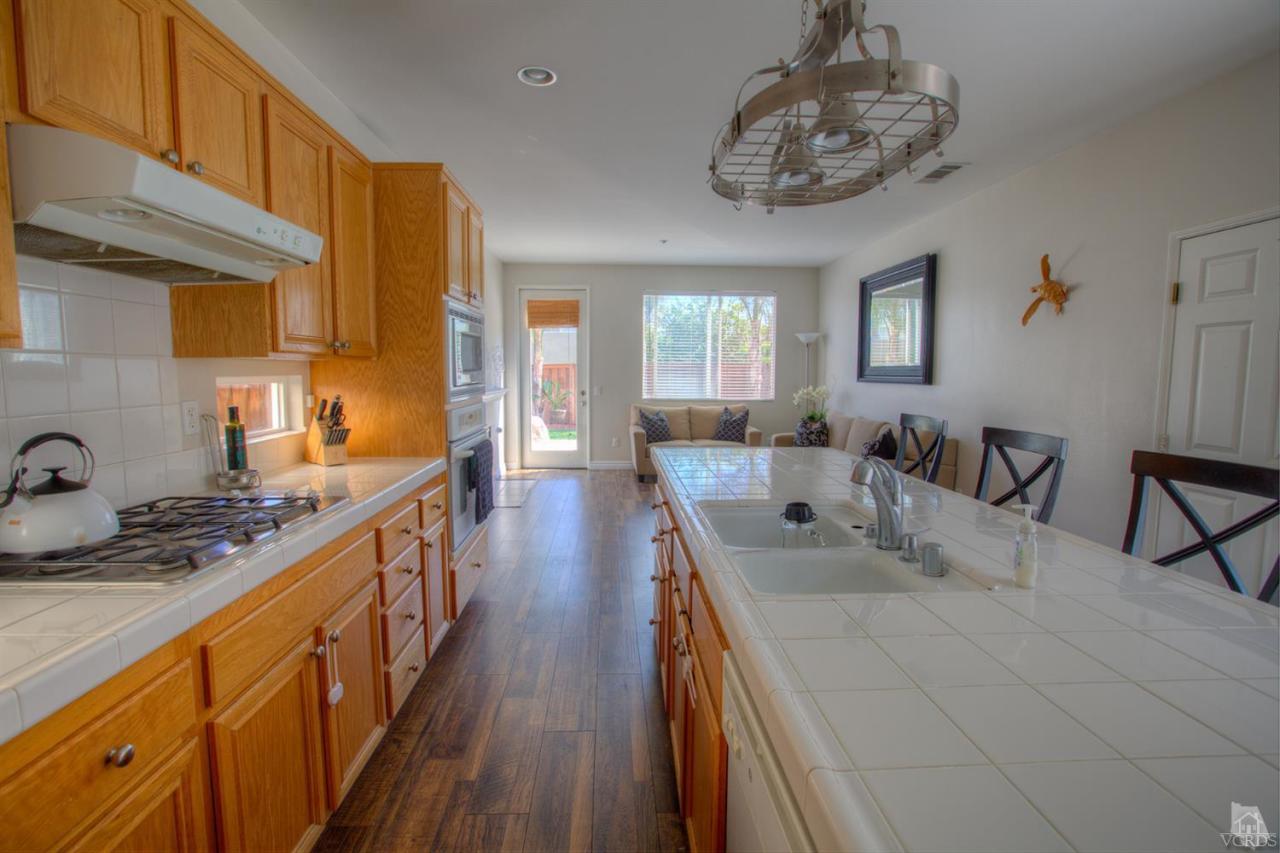 546 Morado Place Oxnard, CA 93030 - Photo 8 of 41 a kitchen with stainless steel appliances granite countertop a sink dishwasher stove and refrigerator with wooden floor