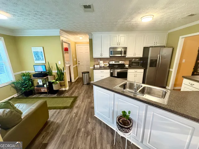 a kitchen with stainless steel appliances granite countertop a refrigerator a stove and a sink
