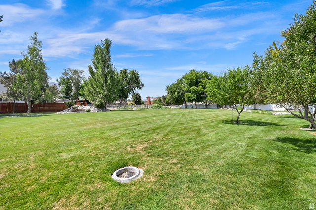 13658 South Fort Street Draper, UT 84020 - Photo 74 of 87 Expansive lawn area featuring mature trees, perimeter fencing, and a built-in fire pit