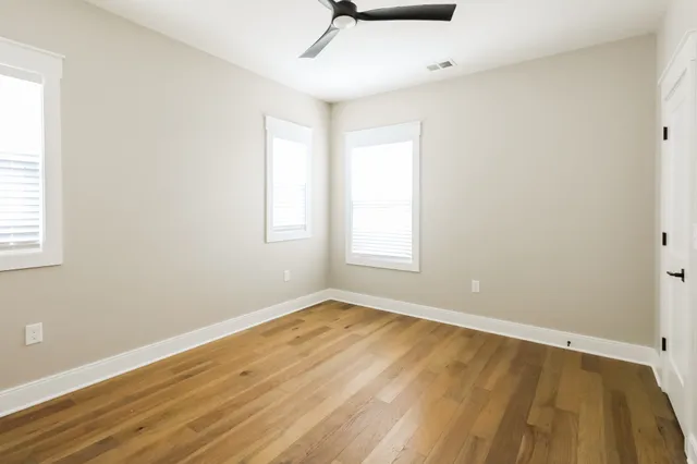 an empty room with wooden floor and windows