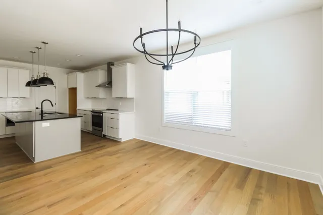 a kitchen with stainless steel appliances granite countertop a sink a stove and a wooden floors