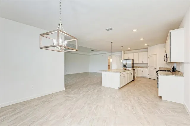 a view of a kitchen with kitchen island stainless steel appliances wooden floor and a chandelier