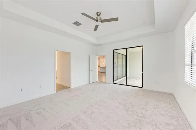 an empty room with windows and ceiling fan