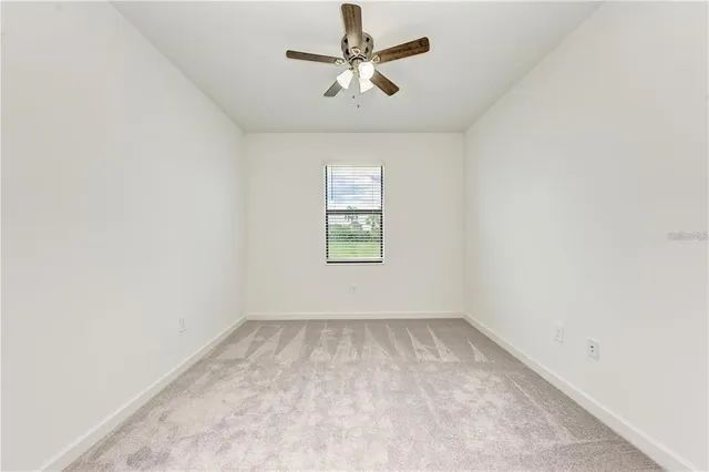 an empty room with windows and ceiling fan