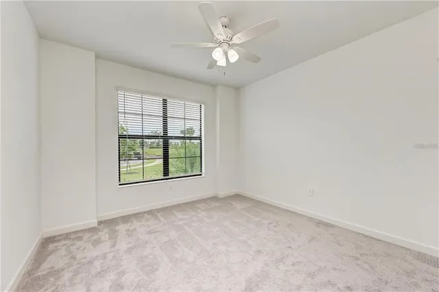 an empty room with chandelier fan and windows
