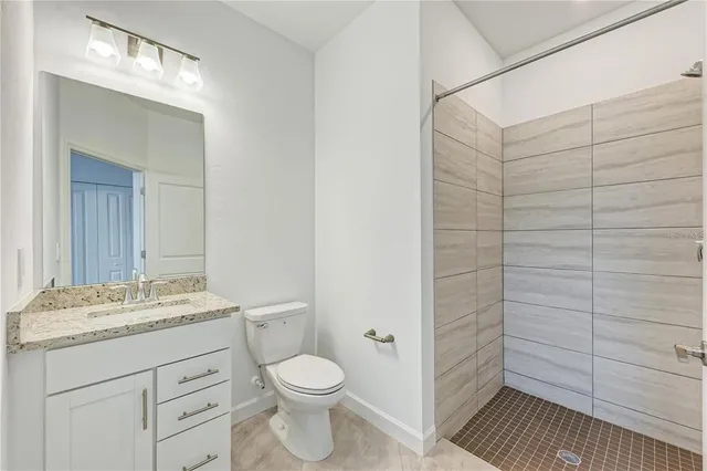 a bathroom with a granite countertop toilet a sink a mirror and shower