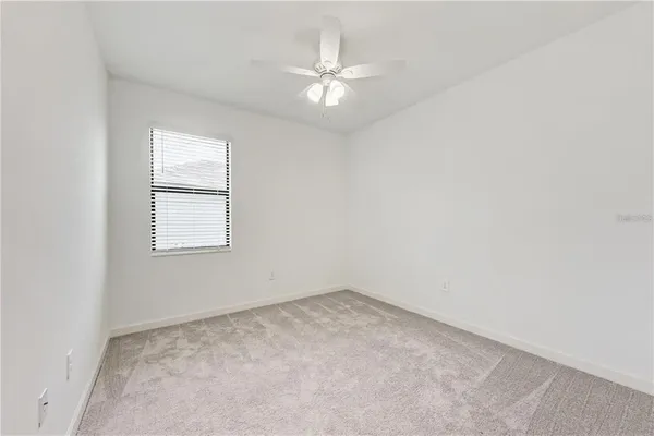an empty room with a window and a fan